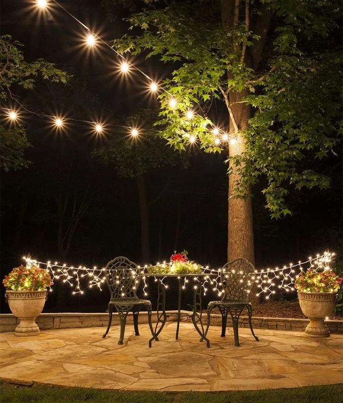 outdoor patio lights metal garden furniture fairy lights hanging from pots of plants strings of lights above hanging from tree