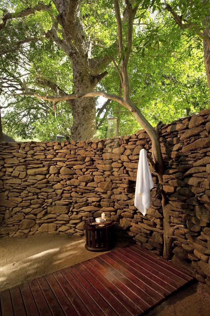 outdoor shower ideas wall made of rocks tree growing out of it shower with wood floor
