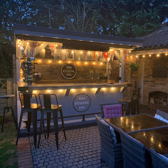 outside bar ideas brick walls wooden enclosure bar with string lights wine bottle stand two metal bar stools