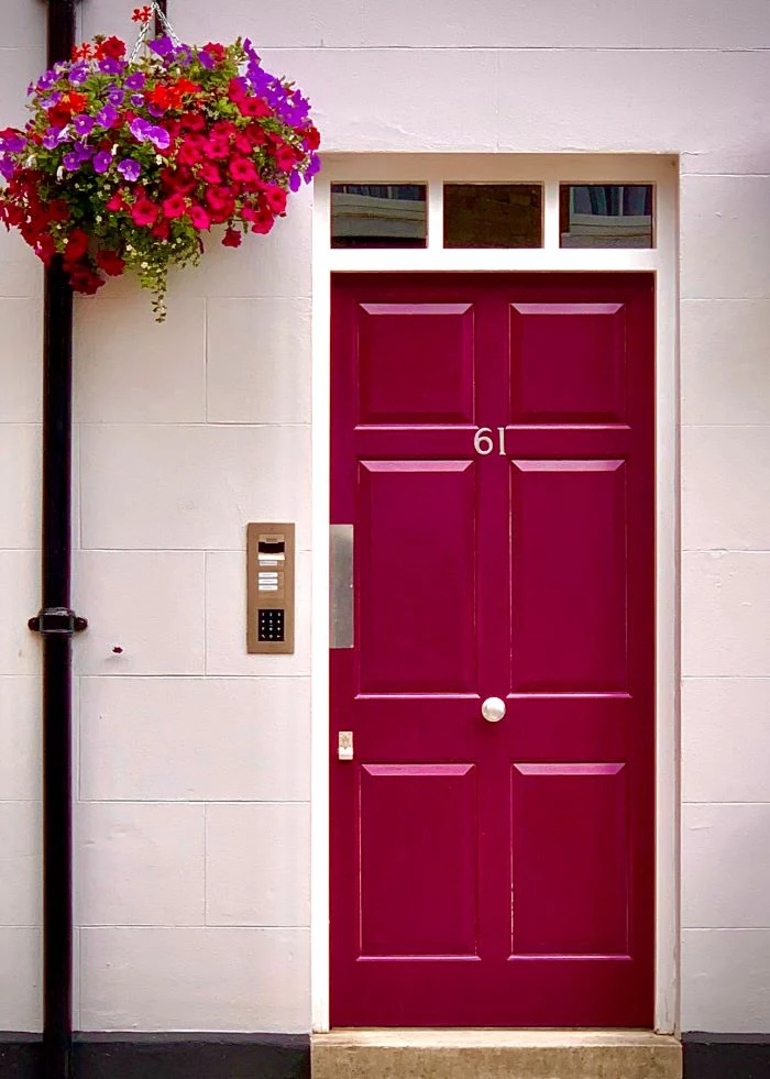 pink wooden door of house door installation large flower bouquet hanging above it