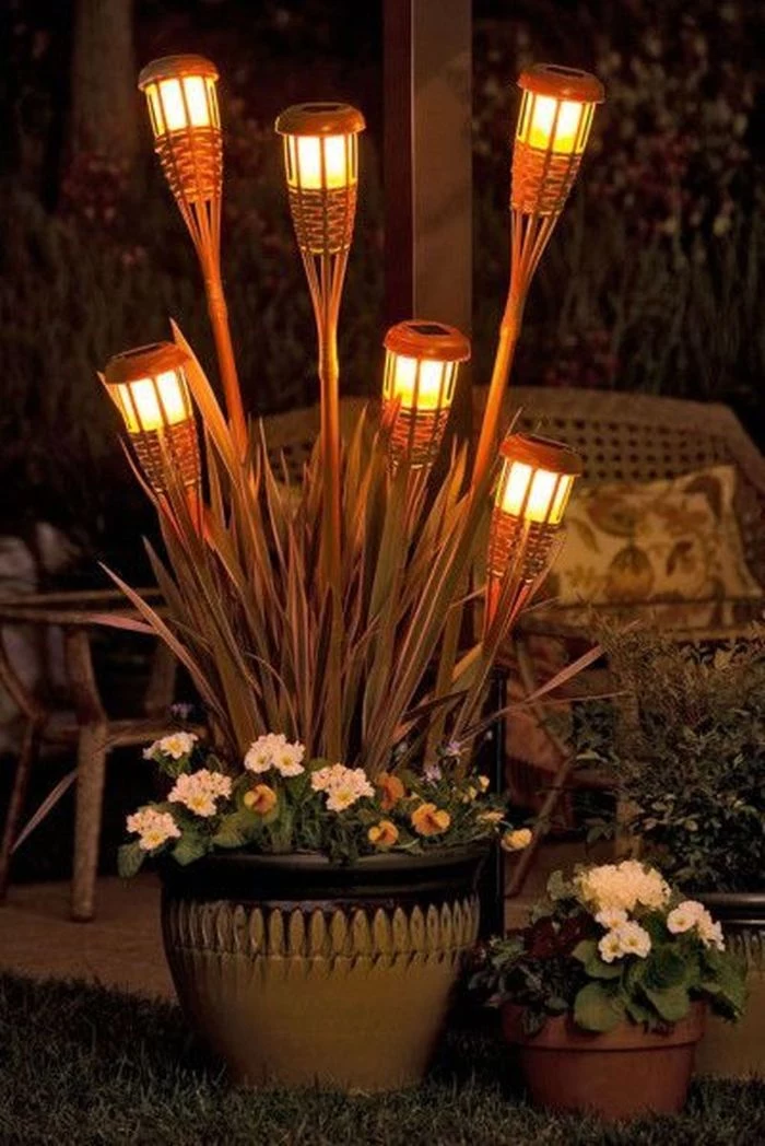 planters with flowers string light pole six solar panel torches stuck in them placed next to lounge area