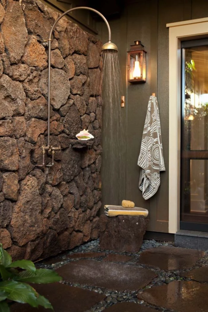 rock wall with vintage shower head and faucet outside showers stone tiles and small rocks on the floor