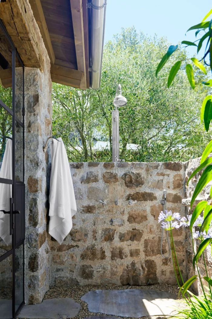 rustic style wall made of stone how to build an outdoor shower shower head mounted on it towel hanging on the side
