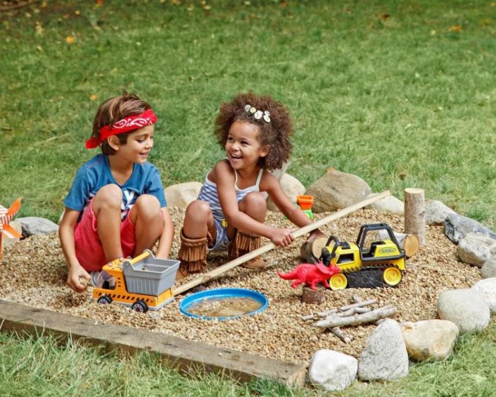 sandlot with toys and boulders around it outdoor activities for kids boy and girl playing inside