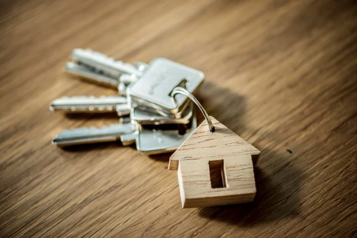 set of keys with a keychain in the shape of a house placed on wood surface house in spain