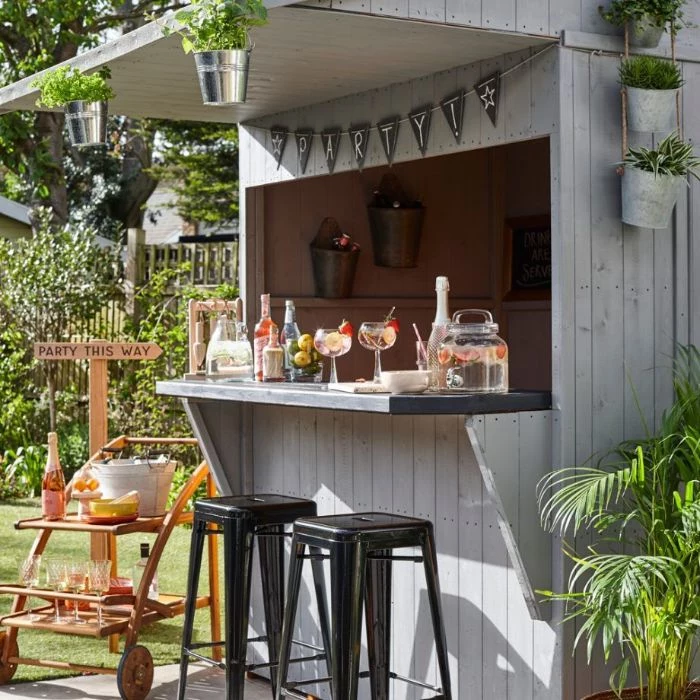 shed turned into bar made of white wood outdoor bar ideas two black stools in front mimosa cart