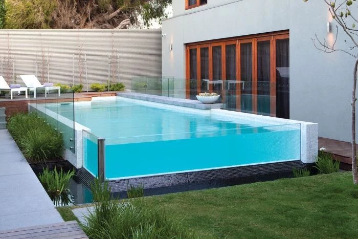small above ground pool with glass walls small backyard pools two lounge chairs on deck next to it