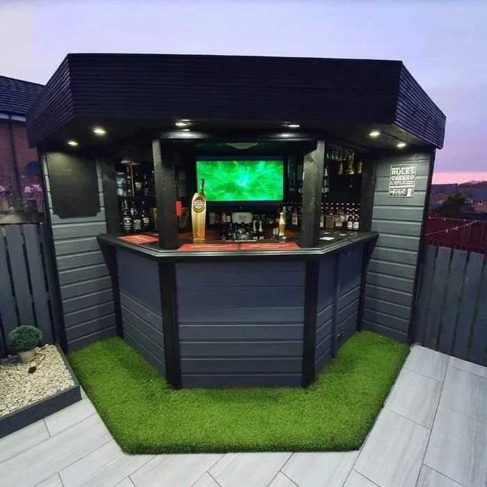 small garden bar made with black and grey wood outdoor bar ideas tv inside lots of bottles on the shelves