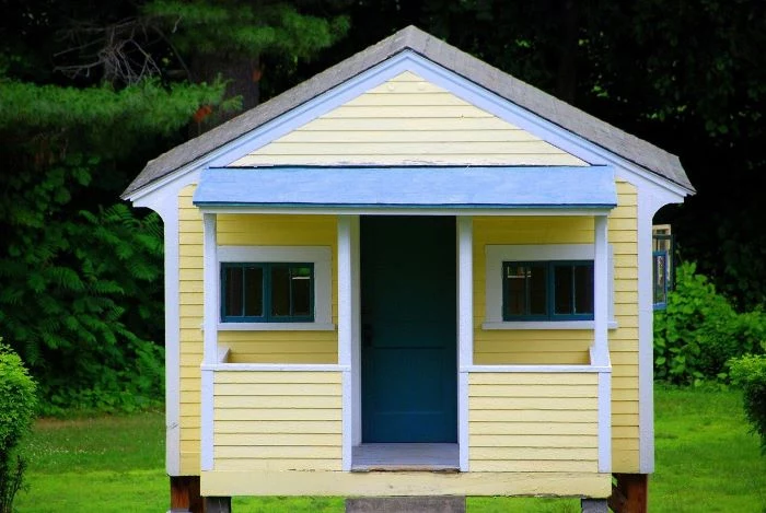 small house covered with yellow siding home siding blue frames on door windows roof