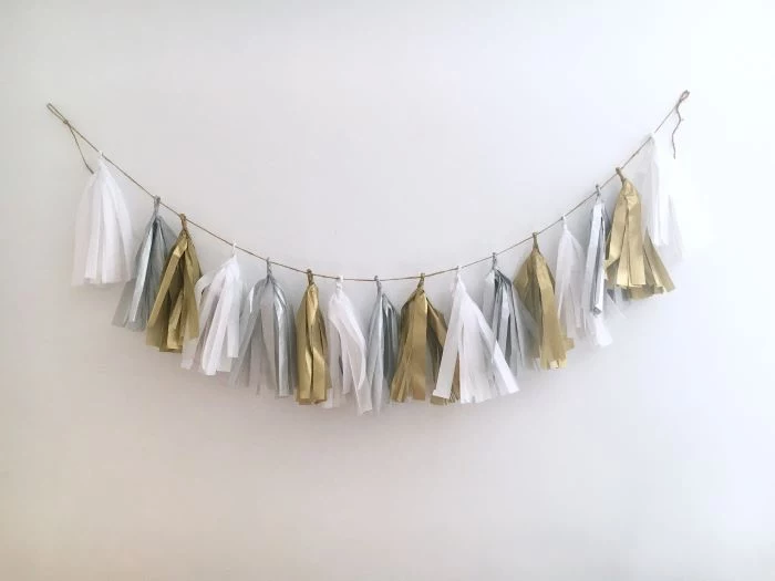 tassel garland in white silver and gold hanging on white wall baby shower centerpiece ideas
