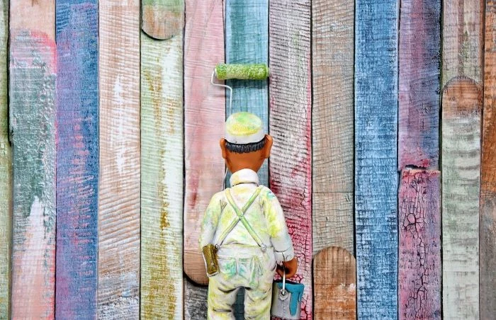 toy of man wearing protective gear and hat carrying a bucket of paint lead poisoning painting colorful wall