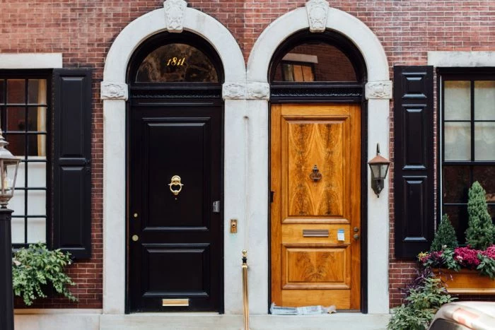 two doors side by side on two different houses door installation one black one natural wood