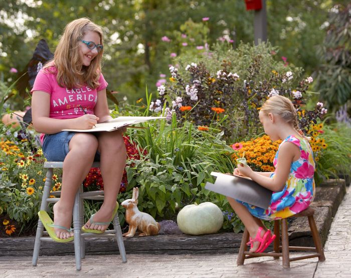 two girls different ages drawing outside outdoor activities for toddlers holding pencils sitting on chairs