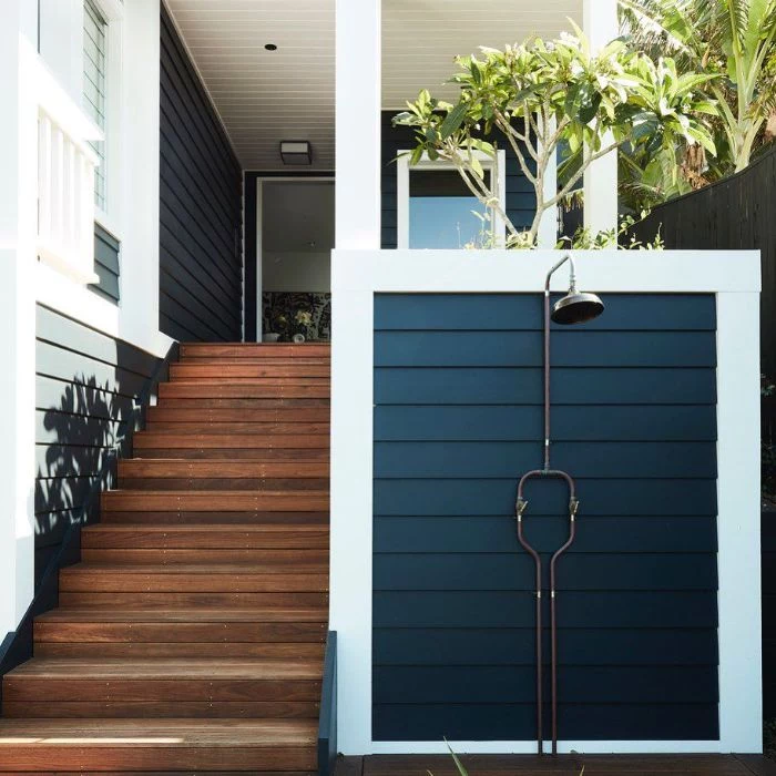 white and navy blue wood wall next to staircase building an outdoor shower metal shower mounted on it