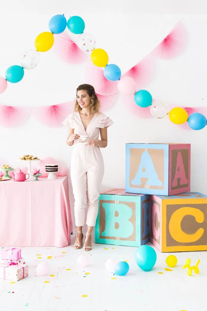 woman standing next to dessert table baby blocks baby shower decoration ideas for girl balloon garlands on the wall