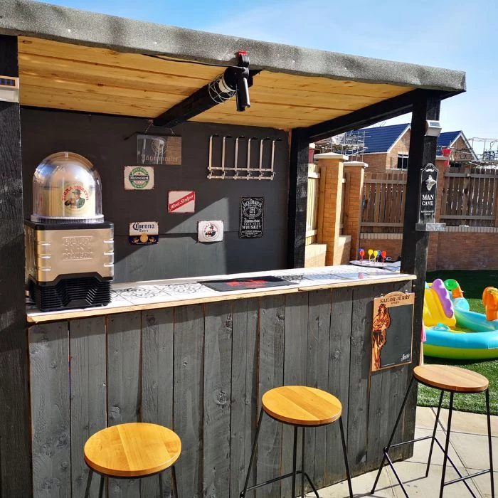 wooden enclosure in black with three bar stools diy outdoor bar next to kiddie pool