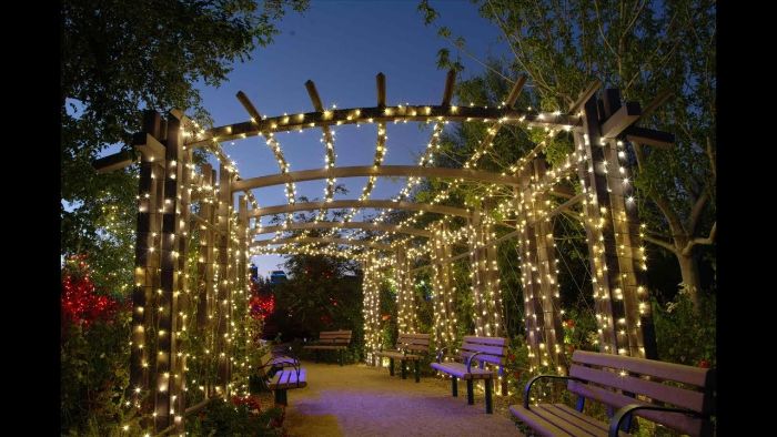 wooden poles above benches wrapped in strings of fairy lights landscape lighting ideas