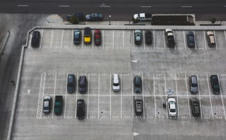 aerial photo of parking lot parking spot in the city half filled with parked cars