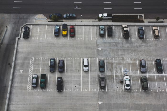 aerial photo of parking lot parking spot in the city half filled with parked cars