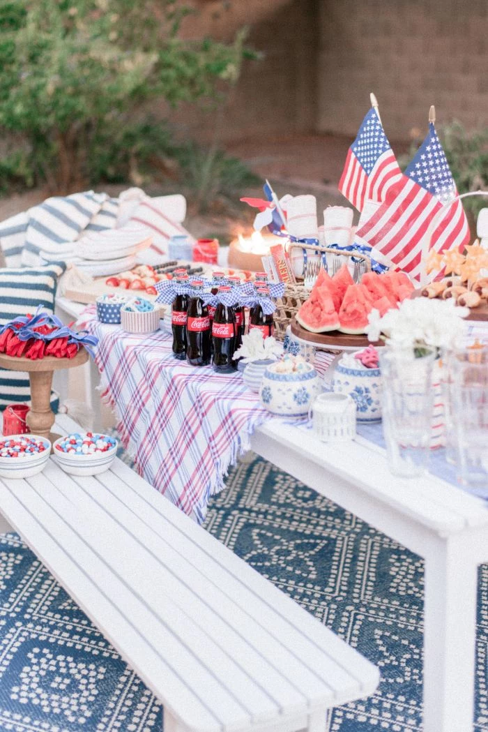 bench and table decorated with american flags fourth of july decorations different food and drinks on it