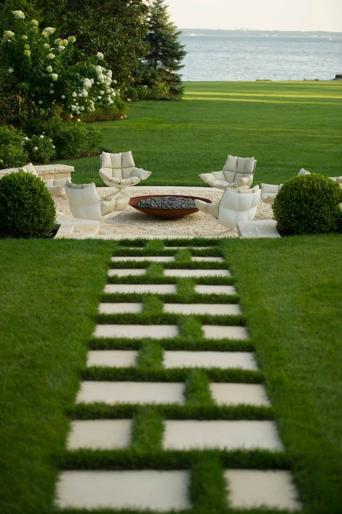 bench made of stones lounge chairs with white cushions arranged around homemade fire pit made of metal and rocks