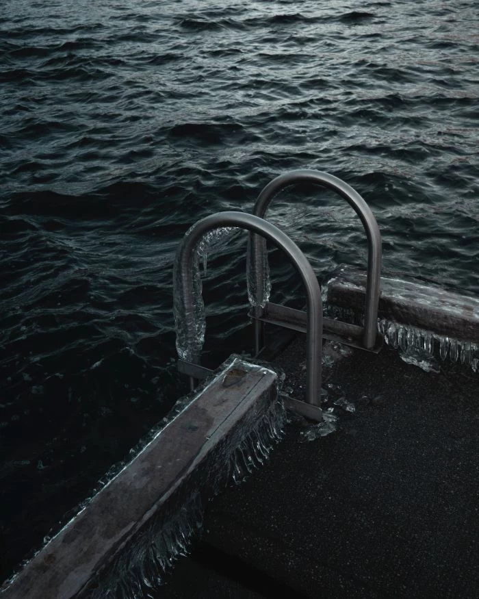 black and white photo of swimming pool ladder installing a swimming pool frozen with ice on it