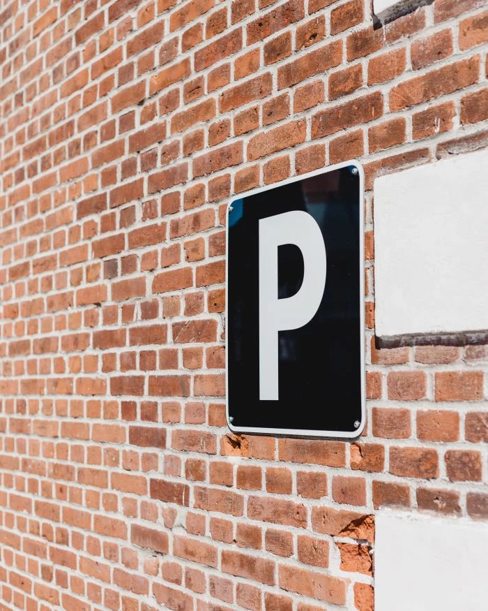 black parking sign hanging on brick wall parking spot in the city