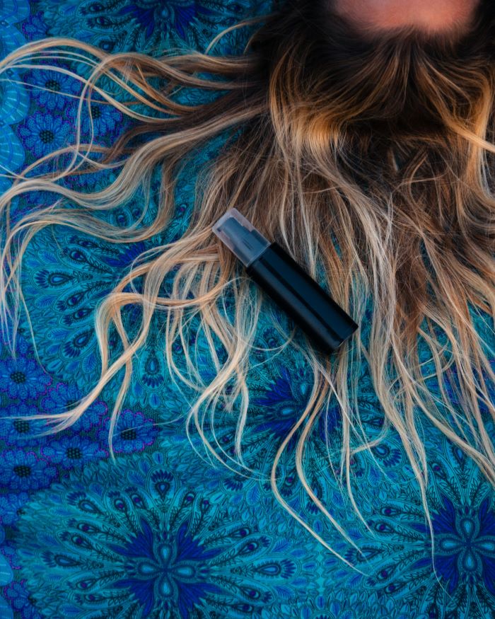 black spray bottle placed on blonde hair avoid bad hair days spread out on blue cloth