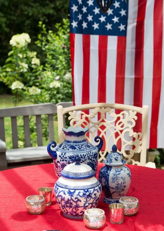 blue and white vintage vases jars in the middle of table patriotic decorations american flag in the background