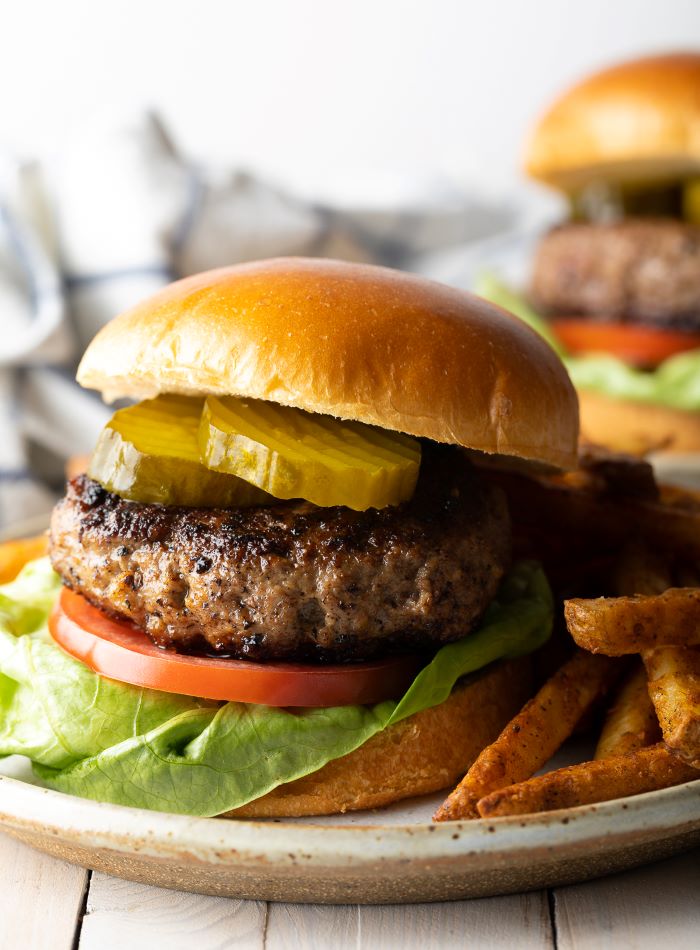 burger with pickles tomatoes lettuce best hamburger recipe placed on plate next to french fries