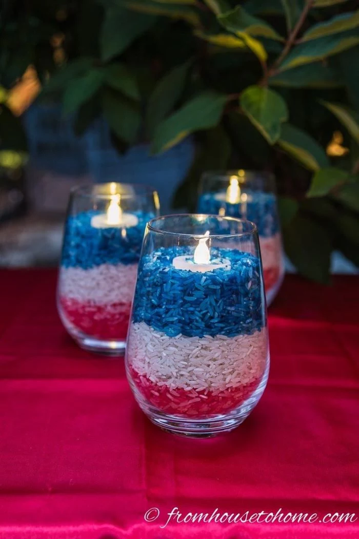 candleholders filled with rice dyed in red white and blue diy 4th of july decorations placed on red table cloth