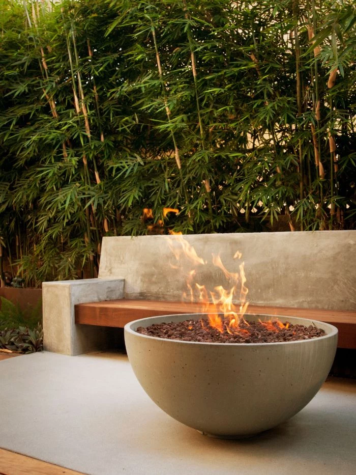 concrete bowl filled with rocks fire burning inside how to make a fire pit bench next to it made of stone and wood