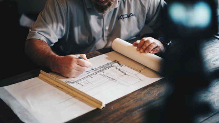construction business ideas man sitting at table architect plans in front of him