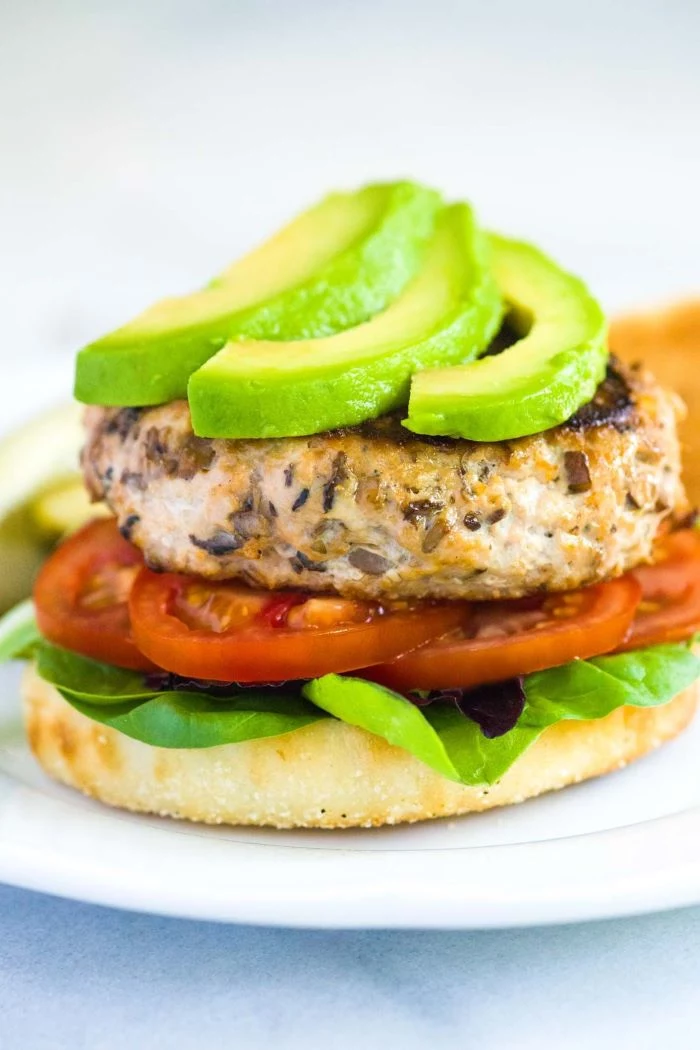 easy hamburger recipes turkey burger with tomatoes lettuce avocado placed on white plate