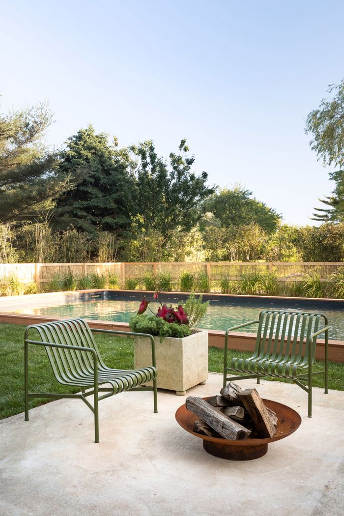 green metal chairs next to small metal bowl filled with wooden logs homemade fire pit