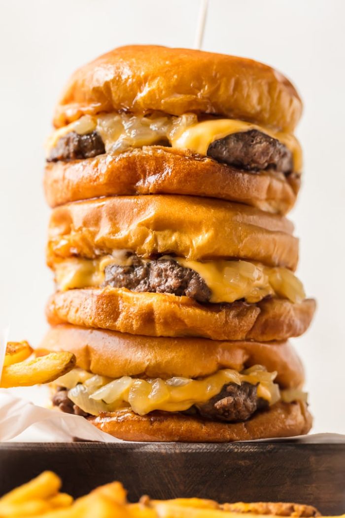 hamburger recipes three cheeseburgers stacked on top of each other placed on wooden board