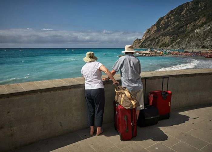 man and woman leaning on balcony overlooking the ocean travel tips suitcases bags next to them
