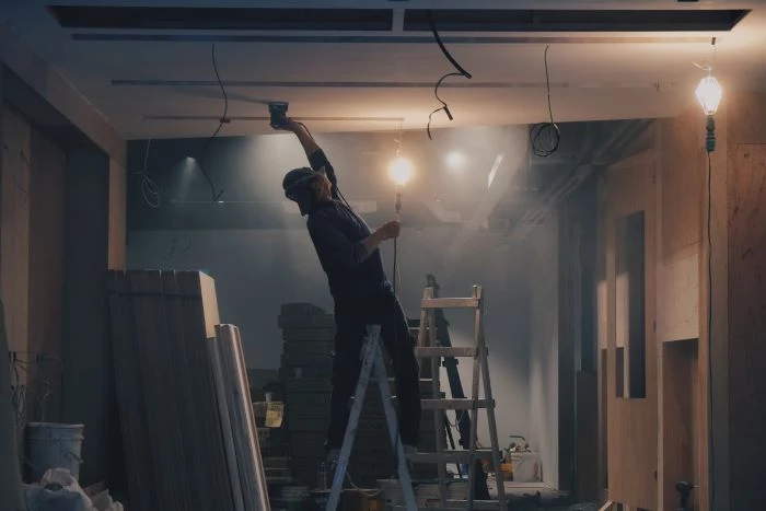 man wearing protective gear on top of ladder construction business ideas working on ceiling