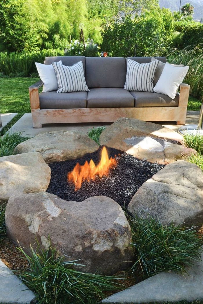 outdoor fire pit ideas five large rocks arranged in circle filled with gravel wooden sofa with gray cushions