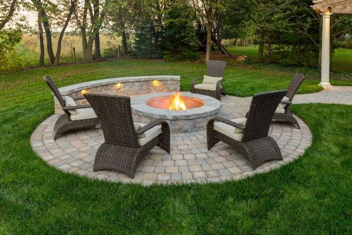 rattan furniture arranged around round fire pit made of stone fire pit seating ideas