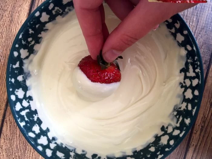 strawberry being dipped into melted white chocolate traditional 4th of july foods