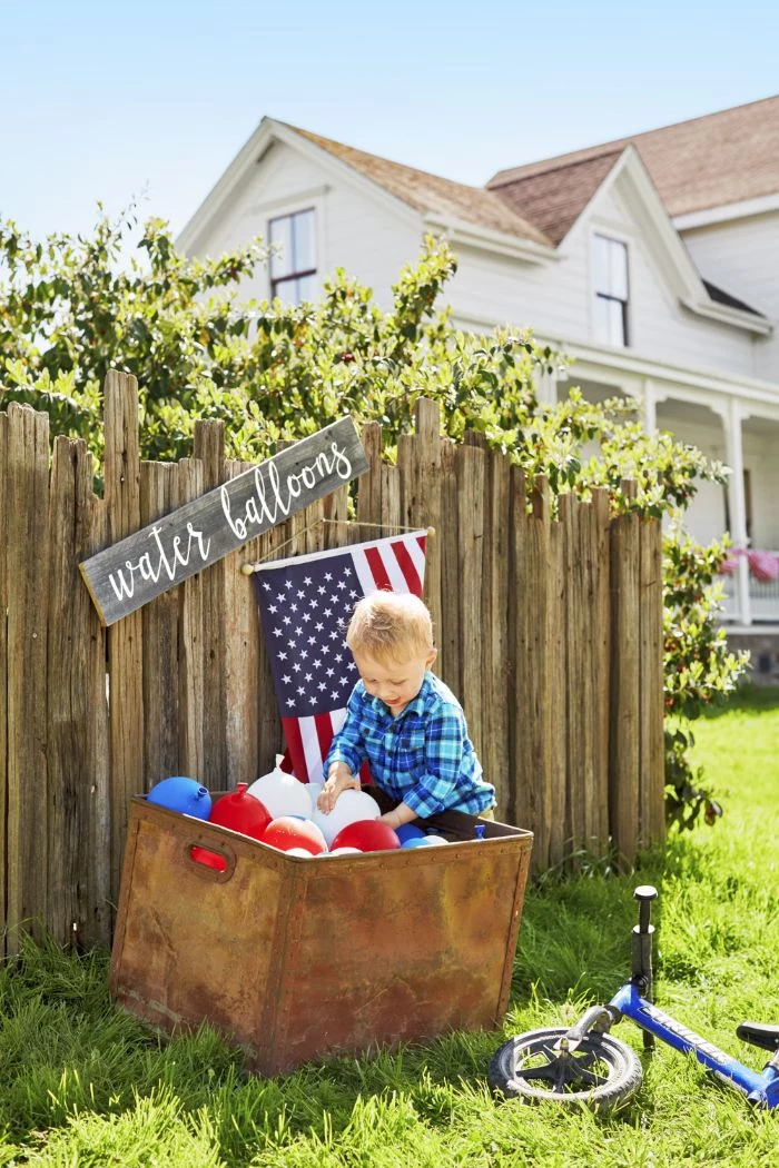 toddler taking out water balloons from crate fourth of july decorations red white and blue balloons