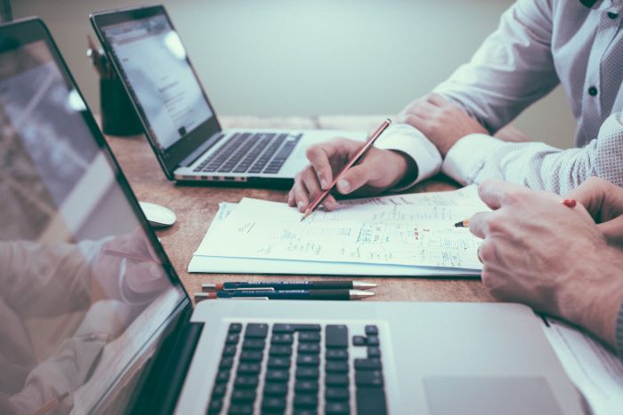 two laptops on wooden table construction business ideas men looking at documents