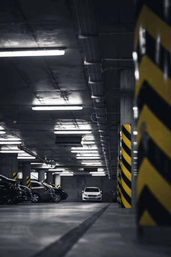 white car driving into underground parking parking spot in the city led lights on the ceiling