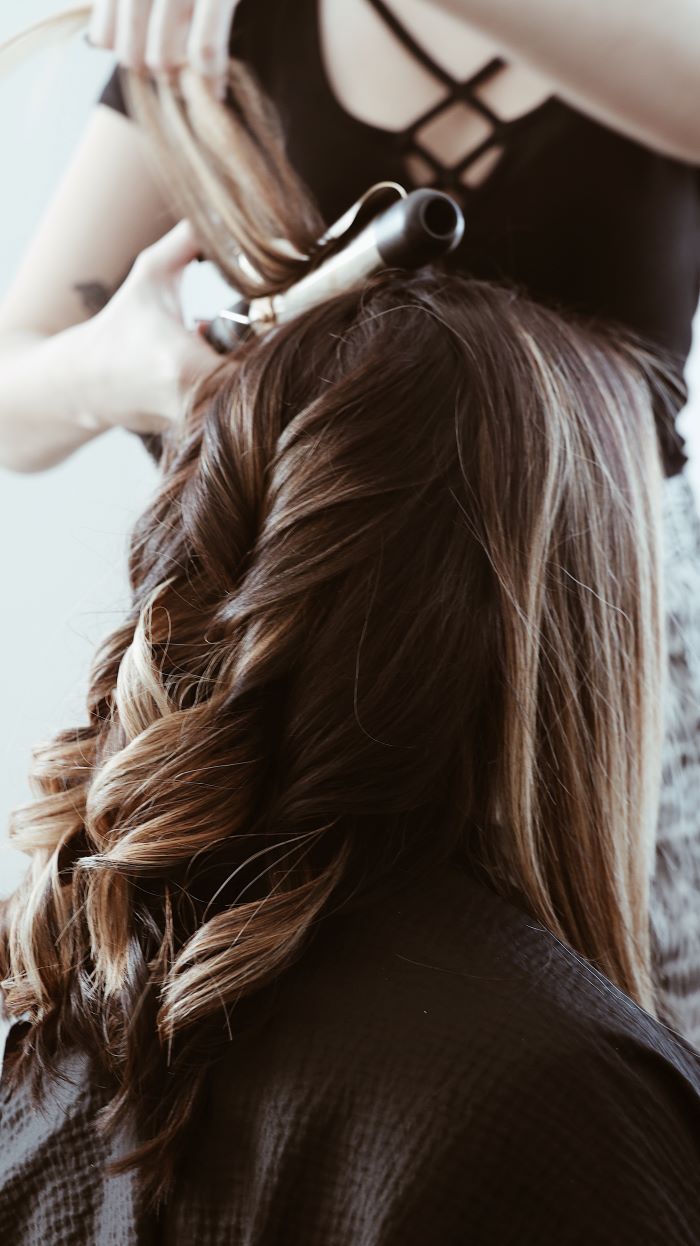 woman styling another womans hair with hair curler avoid bad hair days