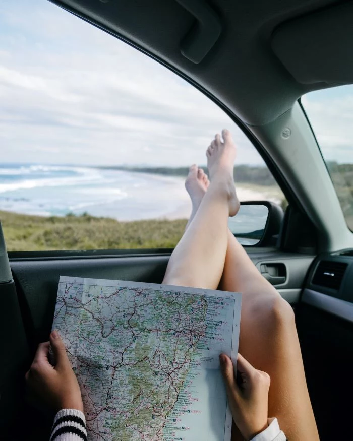 woman with feet leaning on car window travel tips holding a map