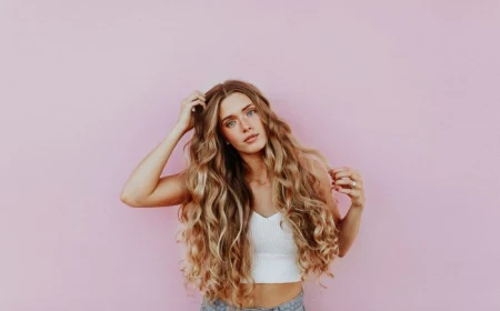 woman with very long blonde wavy hair avoid bad hair days wearing white crop top jeans