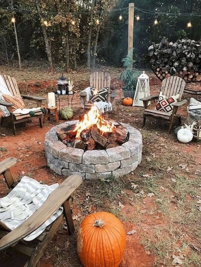 wooden lounge chairs around backyard fire pit ideas made from rocks lanterns and pumpkins around it