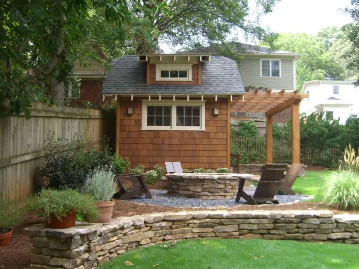 wooden shed in ground fire pit lounge chairs in front arranged around stone round fire pit