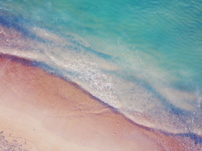 beach aesthetic wallpaper blue waves crashing into a sandy beach with small rocks